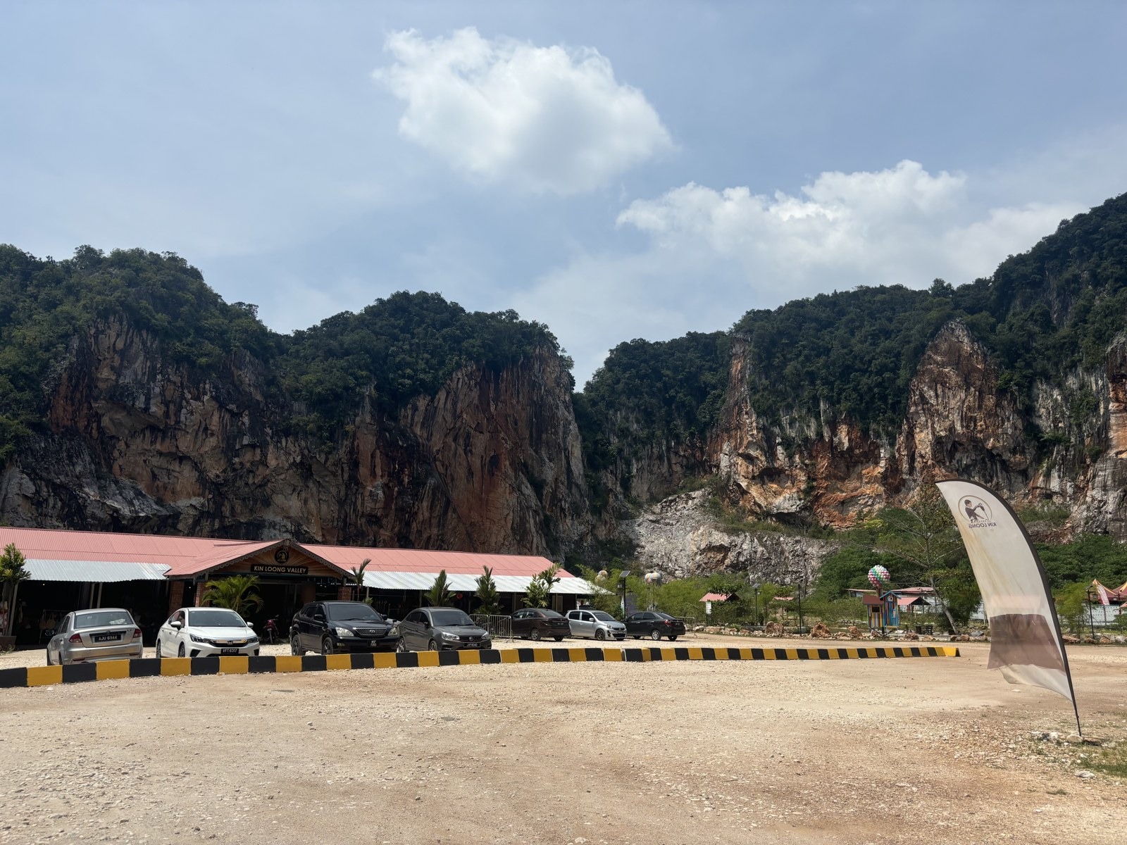 砂利の駐車場とKIN LOONG VALLEYの建物、赤茶色の崖