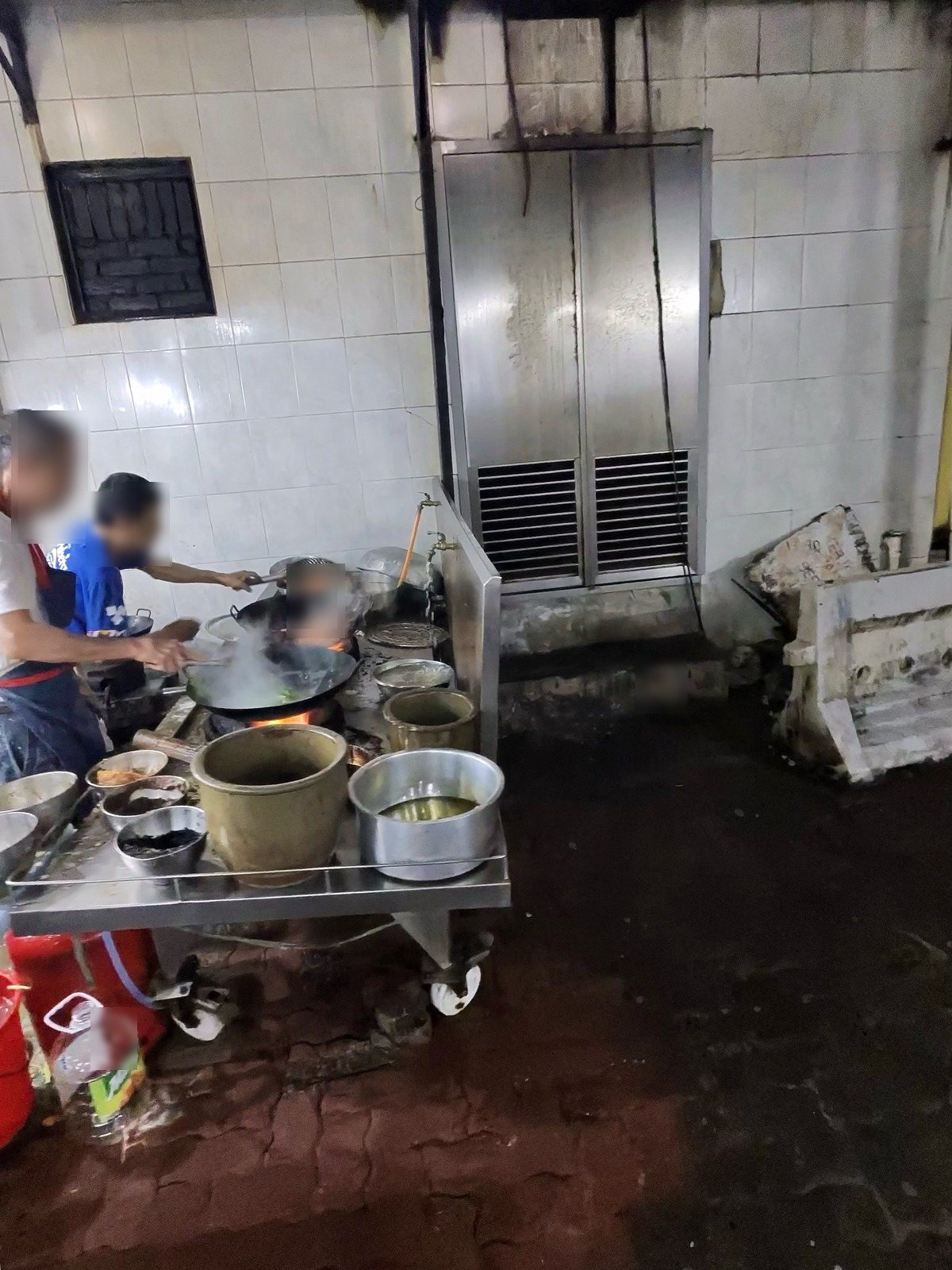 白いタイルの壁の前で中華鍋を振る屋台の料理人