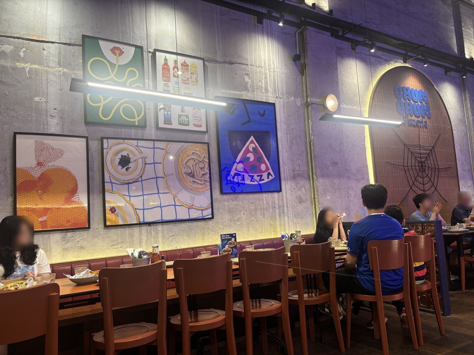 Chum Chum Pizzeriaの店内。ポップな絵の額とクモの巣の飾り