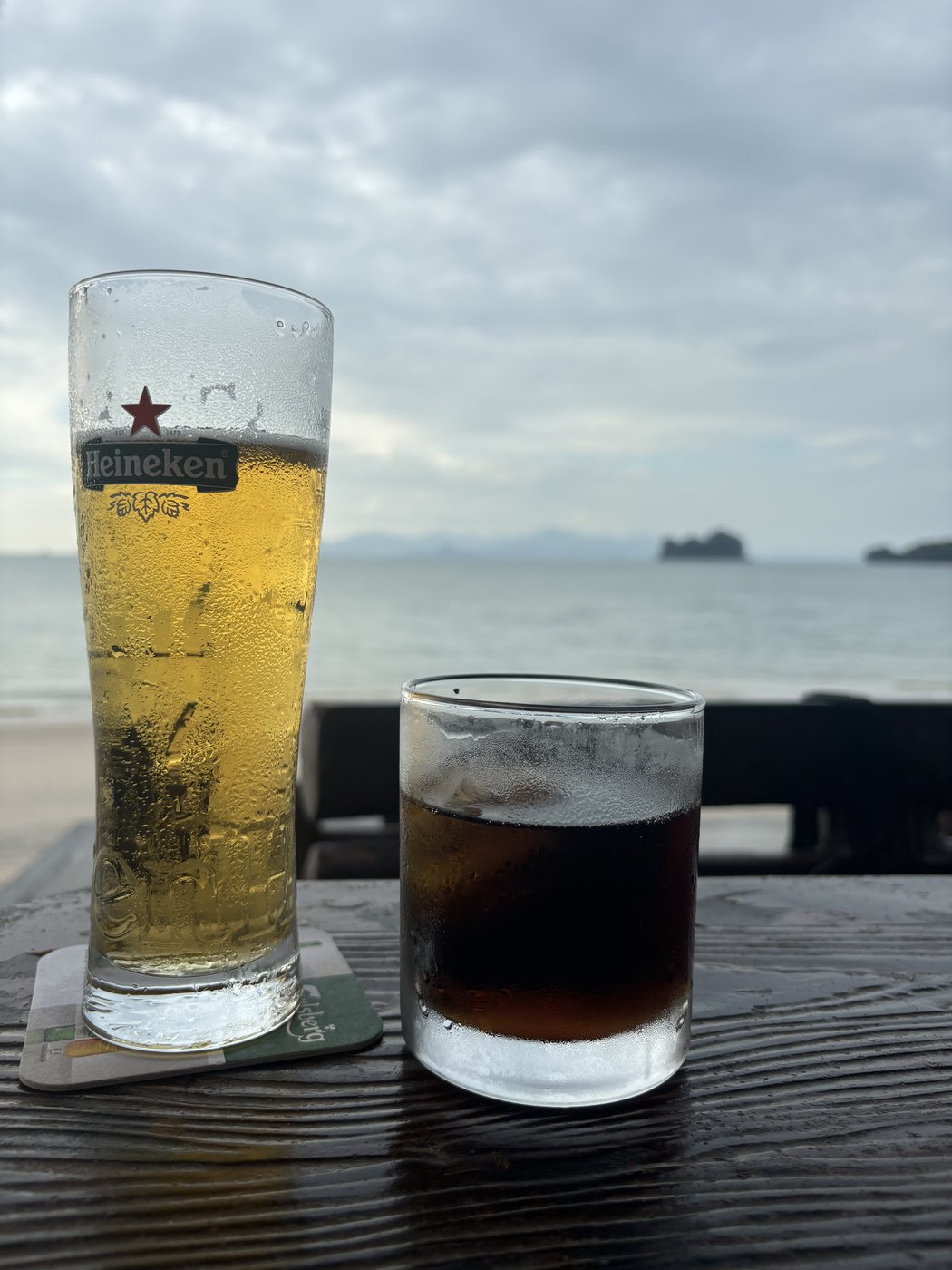 海に面した席のハイネケンの生と氷の入った黒い飲み物、沖の島