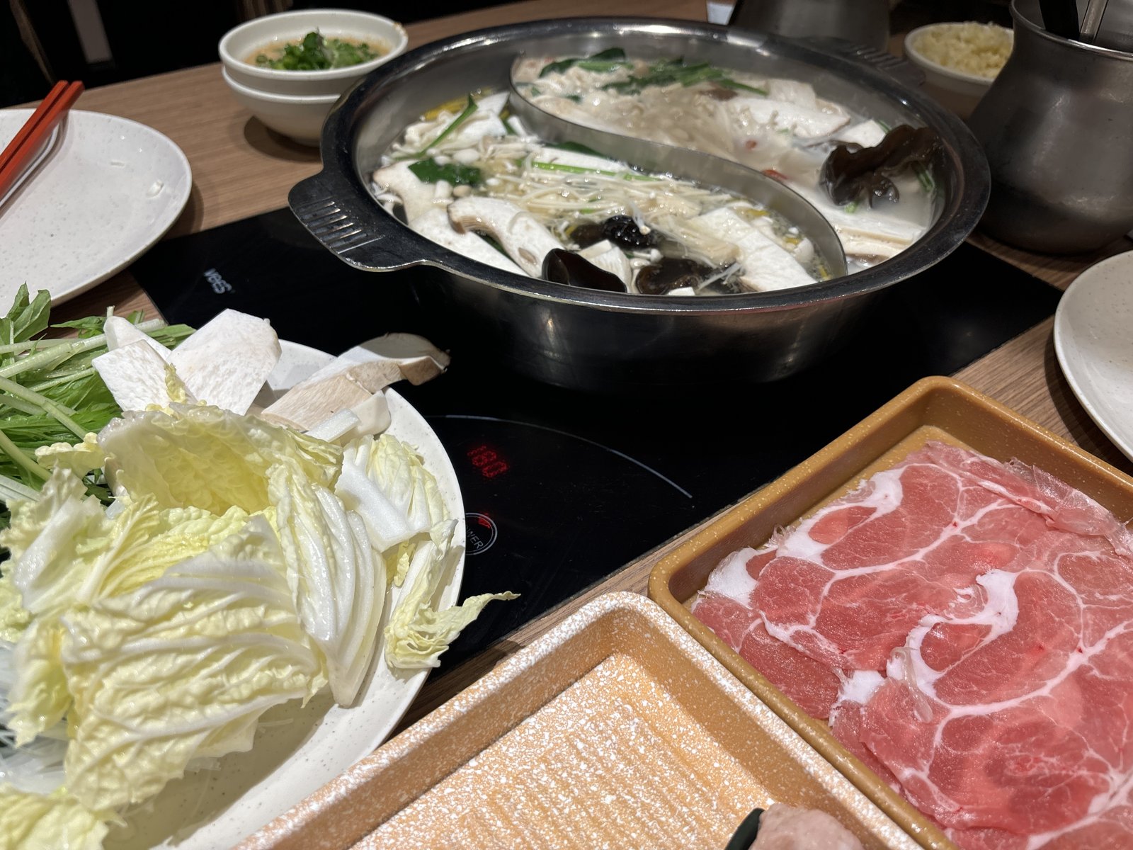 仕切りのある鍋と白菜、薄切りの肉のトレー