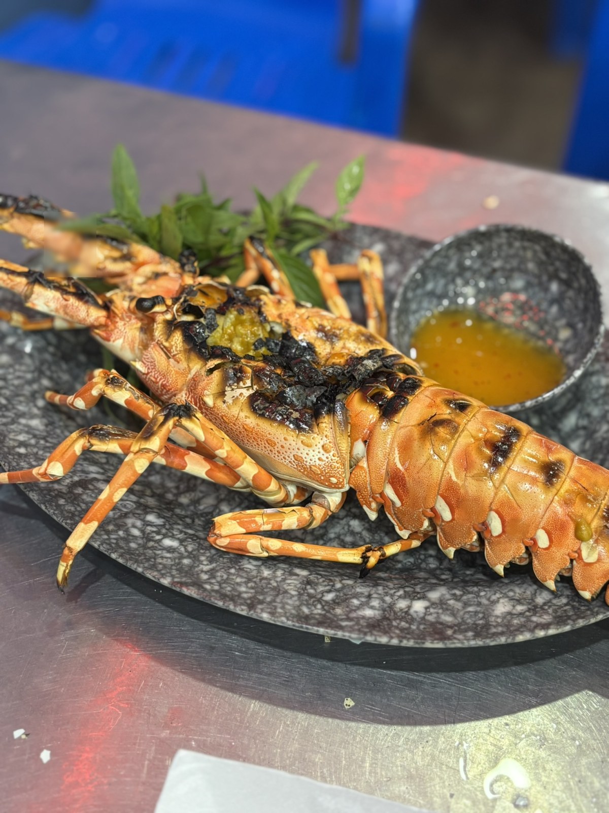 黒い石の皿に載った炭火焼きのイセエビ