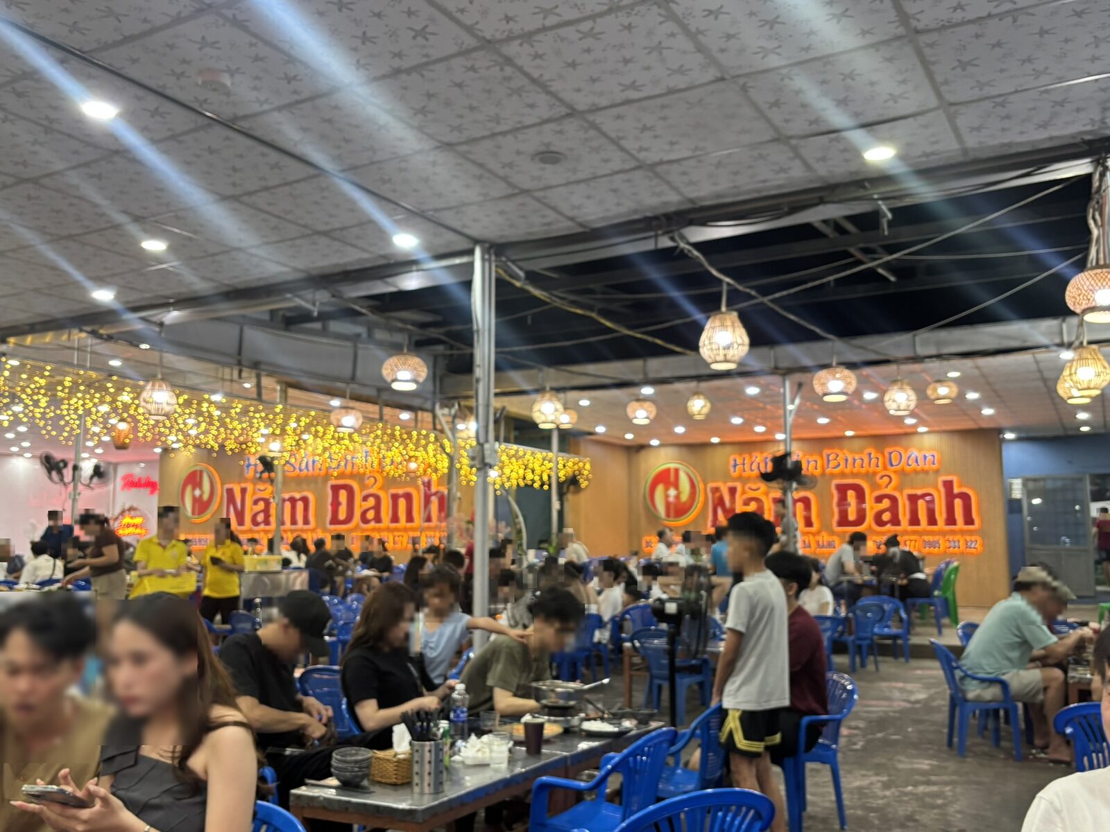 Hai San Binh Dan Nam Danhの看板と青い椅子の屋外ホール