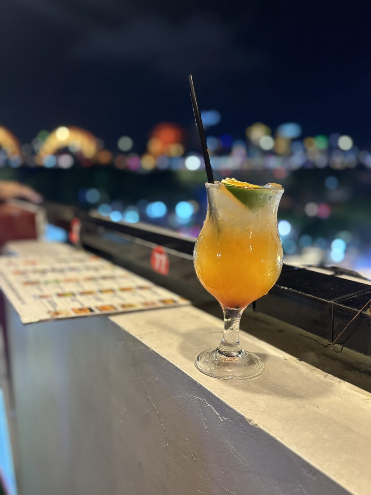 夜景を背にしたオレンジ色のカクテル