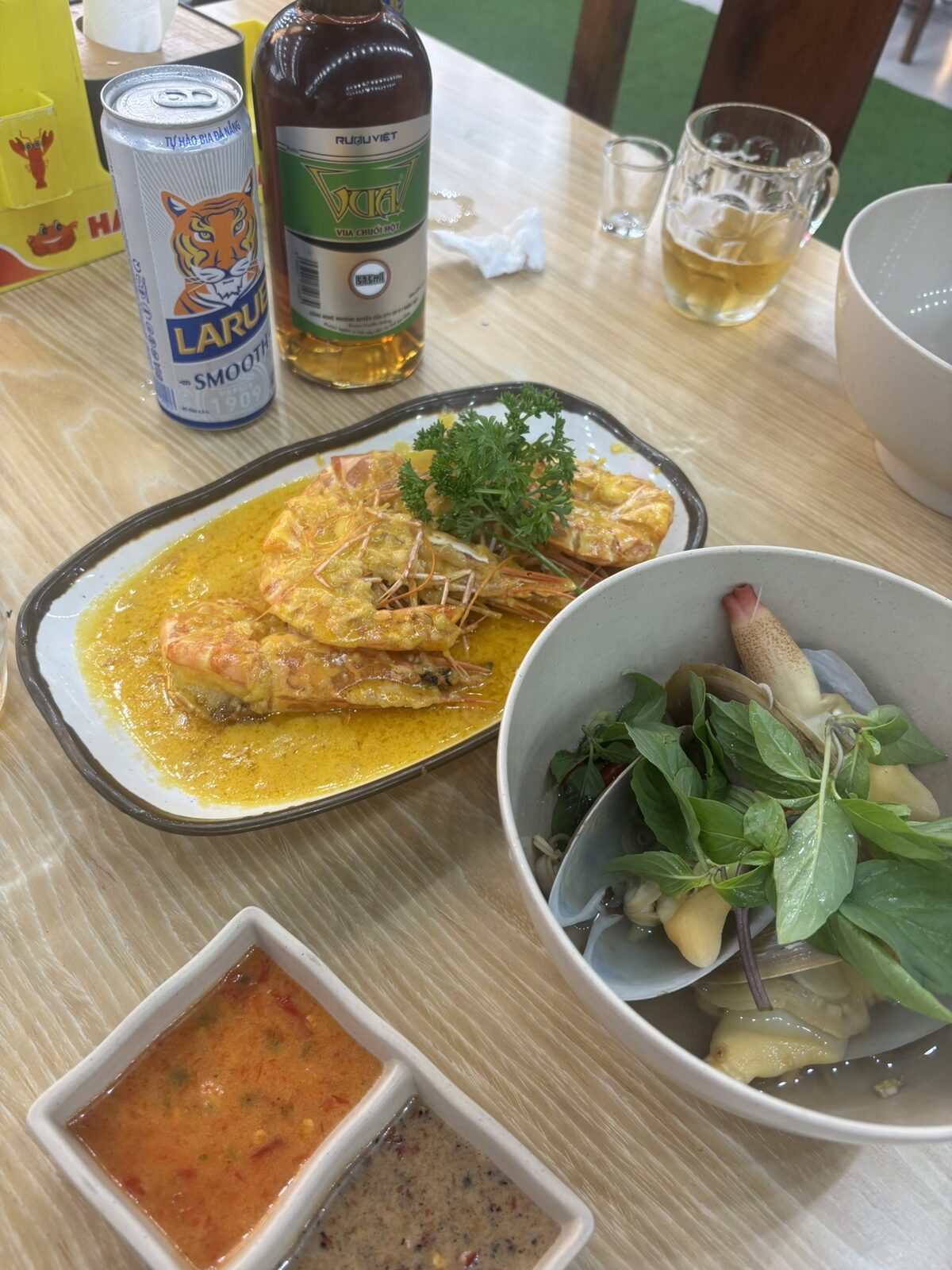 黄色いソースのエビと青菜の器とLARUEの缶が並んだテーブル